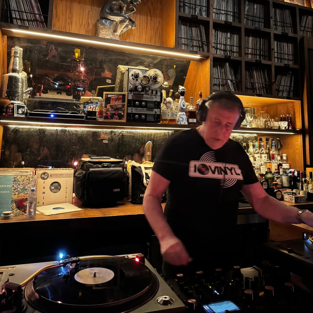 Person operating DJ equipment in a store with 'Dante's HiFi' sign.