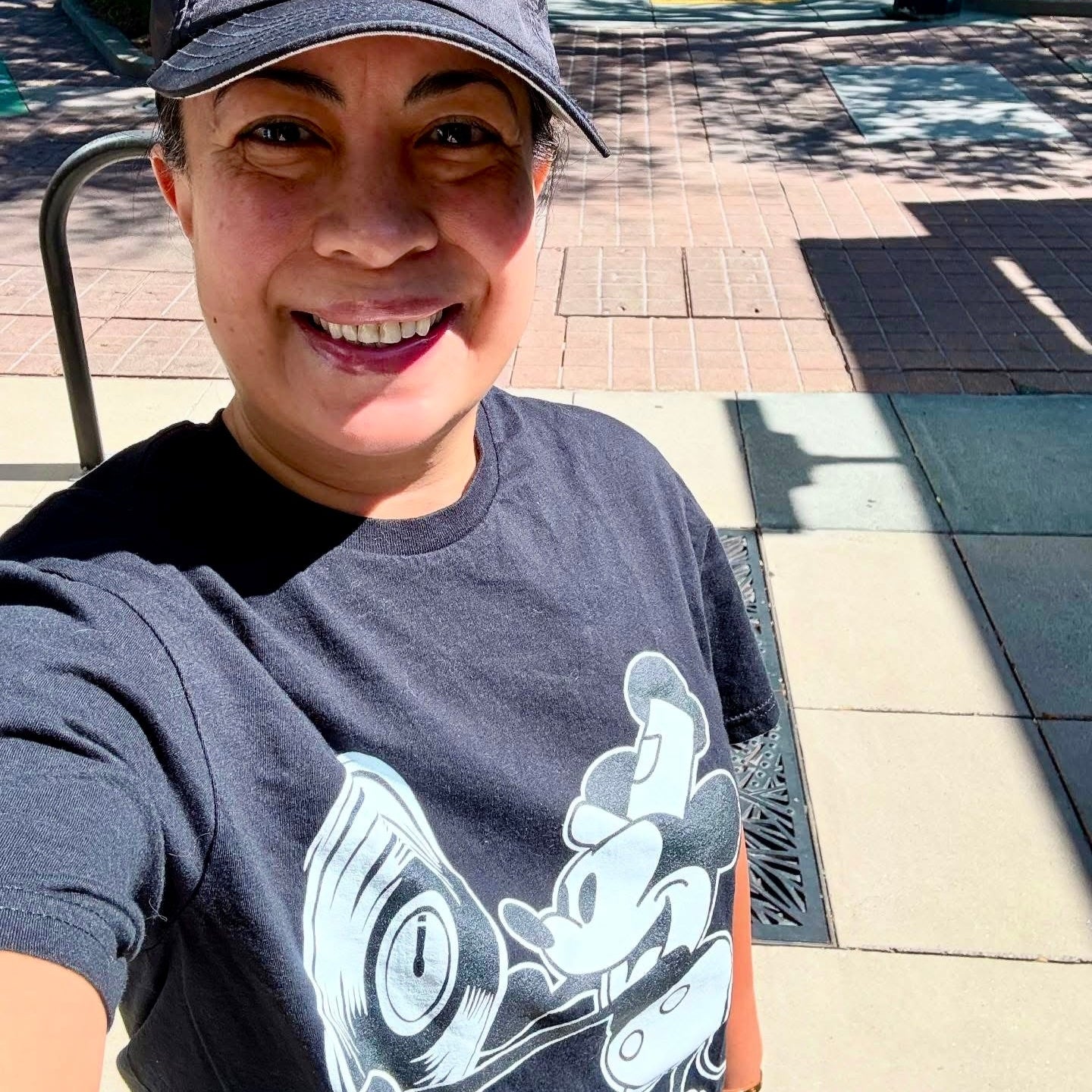 Person wearing a cap and t-shirt on a sidewalk