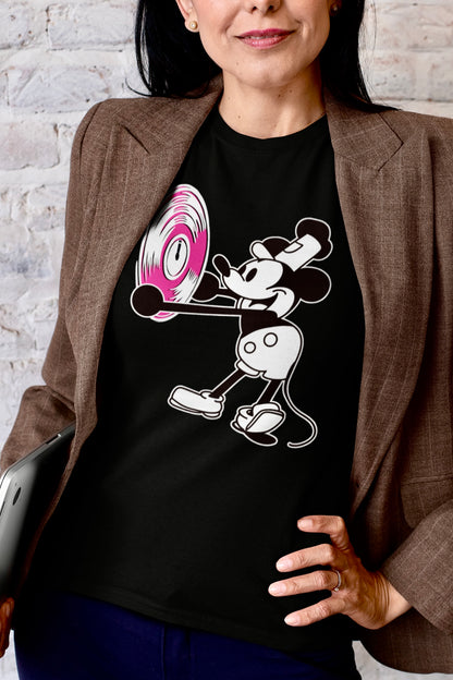 Person wearing a black t-shirt with a cartoon character holding a vinyl record against a brick wall.